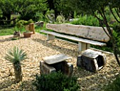 PROVENCE  FRANCE. GARDEN OF MARCO NUCERA. A PLACE TO SIT - CHUNKY WOODEN SEAT IN THE GRAVEL GARDEN