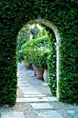 DESIGNER MICHEL SEMINI  PROVENCE  FRANCE. VIEW THROUGH ARCH WITH TERRACOTTA CONTAINERS FILLED WITH HIBISCUS