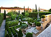 DESIGNER MICHEL SEMINI  PROVENCE  FRANCE. THE FORMAL GARDEN IN THE EVENING WITH BOX EDGED BEDS  BOX BALLS AND CYPRESSES