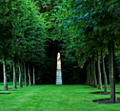 ANGEL COLLINS GARDEN: HORNBEAM AVENUE WITH MIRRORED OBELISK LIT BY DAVID HARBER LIT UP BY THE EVENING SUN. REFLECTION