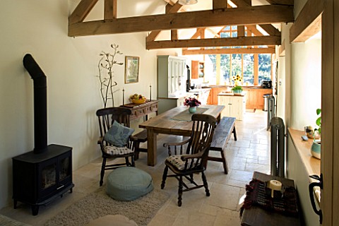 INTERIOR_OF_KITCHEN_WITH_WOOD_BURNER__BESPOKE_FARMHOUSE_TABLE_AND_BENCHES__EXPOSED_ROOF_BEAMS_AND_LI