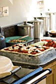 DESIGNER CLARE MATTHEWS  DEVON: THE KITCHEN WITH HOME MADE PIZZA READY FOR COOKING ON TOP OF THE AGA
