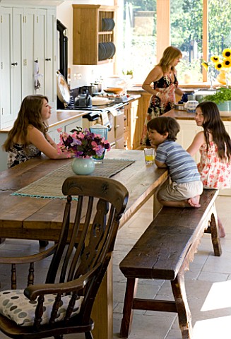 CLARE_MATTHEWS_HOUSE__DEVON_CLARE_AND_FAMILY_RELAX_AROUND_THE_FARMHOUSE_TABLE_IN_THE_KITCHEN_AGA_IN_