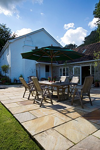 CLARE_MATTHEWS_HOUSE__DEVON_VIEW_FROM_GARDEN_TO_PATIO_AREA_WITH_TABLE_AND_CHAIRS_AND_CANOPY_DESIGNER