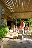 DESIGNER CLARE MATTHEWS: DEVON GARDEN. OUTDOOR SEATING AREA AND OUTDOOR KITCHEN. CLARE ABOUT TO PUT PIZZA IN THE OVEN