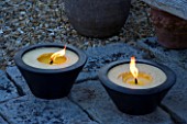 DESIGNER CLARE MATTHEWS: DEVON GARDEN. LIGHTING: TWO LARGE CANDLES IN WOODEN CONTAINERS ON THE PATIO