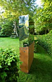 DAVID HARBER SUNDIALS: METAL TITAN SCULPTURE MADE FROM OXIDISED AND MIRROR-POLISHED STAINLESS STEEL STANDS ON LAWN. REFLECTION