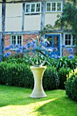 DAVID HARBER SUNDIALS: BRONZE ARMILLARY SPHERE SUNDIAL ON STONE PLINTH IN COTTAGE GARDEN WITH BLUE AGAPANTHUS