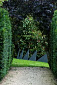 THROUGHAM COURT  GLOUCESTERSHIRE. DESIGNER: CHRISTINE FACER: VIEW ALONG YEW LINED PATH TO ENERGIES - CUMBRIAN BLUE SLATE SCULPTURE