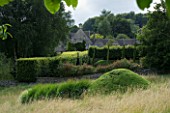 THROUGHAM COURT  GLOUCESTERSHIRE. DESIGNER: CHRISTINE FACER: THE COURT SEEN FROM THE WALNUT QUINCUNX WITH PICO MOUND AND ORNAMENTAL GRASSES