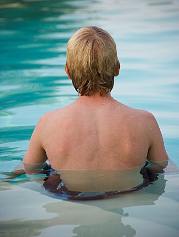 BOY_AGED_13_SITTING_IN_A_SWIMMING_POOL_FACING_FORWARD_SHOWING_BACK
