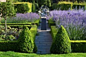 DAVID HARBER SUNDIALS: STONE PATH WITH STAINLESS STEEL ARMILLARY SPHERE SUNDIAL IN FORMAL GARDEN SURROUNDED BY BOX HEDGES TOPIARY AND LAVENDER. EVENING LIGHT