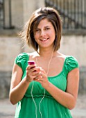 TEENAGE GIRL (16-17 YEARS) IN JEAN MINISKIRT AND GREEN TOP LISTENING TO MP3 PLAYER. TEENAGE GIRLS  ONE TEENAGE GIRL ONLY  IPOD  MUSIC  CASUAL CLOTHING  WAIST UP  SMILING  HAPPY
