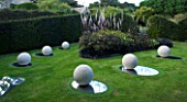 THROUGHAM COURT  GLOUCESTERSHIRE. DESIGNER: CHRISTINE FACER: THE GARDEN OF COSMIC SPECULATION. COSMIC ANCASTER STONE SPHERES & OVAL MIRROR POLISHED STAINLESS STEEL BASE. REFLECTION