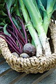 DESIGNER: CLARE MATTHEWS - VEGETABLE GARDEN PROJECT: LEEKS PANCHO AND BEETROOT BOLTHARDY IN A WICKER BASKET ON A WOODEN TABLE