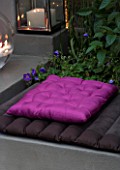 DESIGNER - CHARLOTTE ROWE  LONDON: CHARLOTTE ROWES OWN GARDEN AT NIGHT - PINK CUSHION FROM ZARA HOME ON RENDERED SEAT WITH LIGHT NEARBY