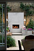 DESIGNER - CHARLOTTE ROWE  LONDON: CHARLOTTE ROWES OWN GARDEN AT NIGHT - VIEW OUT OF BACK DOOR ACROSS PORTUGUESE HONED LIMESTONE FLOORING  RENDERED RAISED BEDS AND FIREPLACE