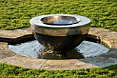 DAVID HARBER SUNDIALS: CHALICE SUNDIAL WATER FEATURE MADE OF MIRROR POLISHED STAINLESS STEEL SITS IN A POOL SURROUNDED BY CAMOMILE LAWN