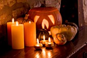 HALLOWEEN: STILL LIFE ON SIDEBOARD AT NIGHT WITH ORANGE CANDLES  PUMPKINS  SQUASHES AND GOURDS