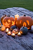 HALLOWEEN: STILL LIFE ON WOODEN TABLE AT NIGHT WITH CANDLES  PUMPKINS  SQUASHES AND GOURDS