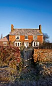 BOONSHILL FARM AT CHRISTMAS. VIEW OF THE FRONT OF THE HOUSE WITH GATE IN FROST. WINTER. DESIGNER LISETTE PLEASANCE