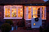 BOONSHILL FARM AT CHRISTMAS. VIEW OF THE KITCHEN FROM OUTSIDE WITH FAIRY LIGHTS ON IN FROST. DESIGNER LISETTE PLEASANCE