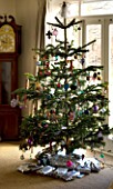 BOONSHILL FARM AT CHRISTMAS: CHRISTMAS TREE IN THE LIVING ROOM WITH PRESENTS BENEATH. DESIGNER: LISETTE PLEASANCE