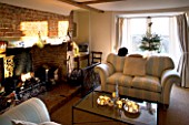 BOONSHILL FARM AT CHRISTMAS: THE LIVING ROOM WITH SETTEES  FIREPLACE  CHRISTMAS TREE BESIDE THE WINDOW. DESIGNER: LISETTE PLEASANCE