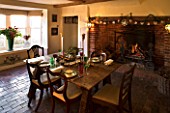 BOONSHILL FARM AT CHRISTMAS: THE DINING ROOM LAID OUT FOR CHRISTMAS WITH CRACKERS  MISTLETOE IN SILVER CONTAINER AND FIRE. DESIGNER: LISETTE PLEASANCE
