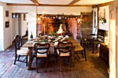 BOONSHILL FARM AT CHRISTMAS: THE DINING ROOM LAID OUT FOR CHRISTMAS WITH CRACKERS  MISTLETOE IN SILVER CONTAINER AND FIRE. DESIGNER: LISETTE PLEASANCE