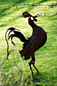 CERNEY HOUSE  GLOUCESTERSHIRE: METAL COCKEREL SCULPTURE IN THE LAWN