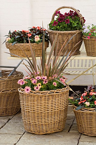 DESIGNERS_SUE_AYLETT_AND_GAY_SEARCH_DISPLAY_OF_WICKER_BASKET_COTTAGE_STYLE_CONTAINERS_ON_METAL_TABLE
