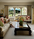 DESIGNERS SUE AYLETT: SUE AYLETTS HOUSE  LONDON: SUE AYLETT SITTING IN THE LIVING ROOM WITH VIEW OUTSIDE TO THE GARDEN
