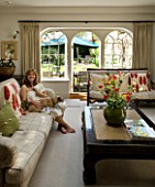 DESIGNERS SUE AYLETT: SUE AYLETTS HOUSE  LONDON: SUE AYLETT SITTING IN THE LIVING ROOM WITH VIEW OUTSIDE TO THE GARDEN