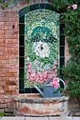 PROVENCE  FRANCE - ALTAVES GARDEN. TILED MOSAIC DESIGN ON WALL OF SUMMERHOUSE WITH WATERING CAN AND FOUNTAIN