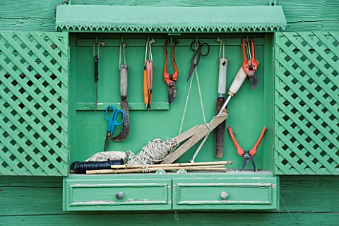 PROVENCE__FRANCE__ALTAVES_GARDENING_TOOLS_HANGING_FROM_GREEN_PAINTED_SHELF_IN_VEGETABLE_GARDEN