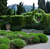 PRIVATE GARDEN  PROVENCE  FRANCE - DESIGNER DOMINIQUE LAFOURCADE. ARCH WITH SOLANUM JASMINOIDES WITH PROSTRATE ROSEMARY BELOW. DRY PLANTING OF ROSEMARY AND ERIGERON KARVINSKIANUS