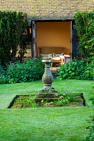 WOLLERTON_OLD_HALL__SHROPSHIRE_VIEW_INTO_SEATING_AREA_IN_SUMMERHOUSE_WITH_STONE_SUNDIAL_IN_THE_ROSE_