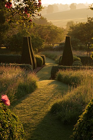 PETTIFERS__OXFORDSHIRE_DAWN_LIGHT_HITS_THE_PARTERRE_FRAMED_BY_ROSE_ARBOUR