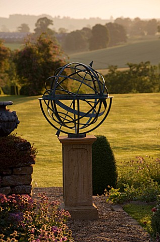 DAVID_HARBER_SUNDIALS_BRONZE_ARMILLARY_SPHERE_SUNDIAL_IN_EVENING_LIGHT_WITH_VIEW_OF_LAWN_AND_COUNTRY
