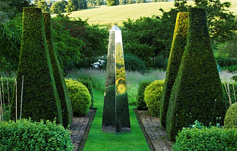 DAVID_HARBER_SUNDIALS_STAINLESS_STEEL_MIRRORED_OBELISK_SUNDIAL_ON_GRASS_PATH_WITH_YEW_TOPIARY_IN_FOR