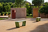 LA NORIA  FRANCE. GARDEN DESIGNED BY ARNAUD MAURIERES AND ERIC OSSART - CONCRETE WALLS AND GREEN BENCHES BESIDE THE GARDEN ENTRANCE - A PLACE TO SIT