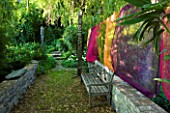 JARDIN DES SAMBUCS  FRANCE - THE STONE BRIDGE WITH MULTI-COLOURED CURTAINS AND WOODEN BENCH