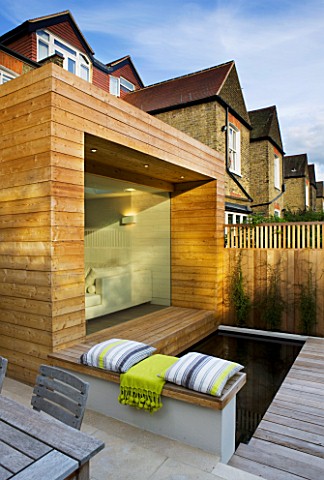 GARDEN_DESIGNER_CHARLOTTE_ROWE__LONDON_GLASS__TIMBER_EXTENSION_AND_DECKPOOL_WITH_THROW_AND_CUSHIONS