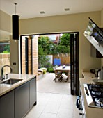 GARDEN DESIGNER: CHARLOTTE ROWE  LONDON: VIEW FROM KITCHEN OUT ONTO FORMAL TOWN/CITY GARDEN WITH TABLE AND CHAIRS