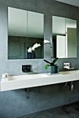 TANIA LAURIE  LONDON. STYLISH  CONTEMPORARY BATHROOM WITH WALL MOUNTED DOUBLE STONE SINK  GREY SLATE WALLS  MIRRORS AND WHITE ORCHID