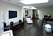 TANIA LAURIE  LONDON. INTERIOR OF LIVING / DINING AREA WITH WALL-MOUNTED TV  WOODEN FLOOR AND CONTEMPORARY FURNITURE