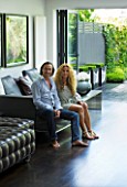 TANIA LAURIE  LONDON. TANIA LAURIE AND HER PARTNER DANIEL IN THEIR CONTEMPORARY LIVING ROOM LEADING OUT ONTO THE GARDEN DESIGNED BY CHARLOTTE ROWE