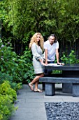 TANIA LAURIE  LONDON. TANIA LAURIE AND HER PARTNER DANIEL IN THEIR SMALL CONTEMPORARY GARDEN DESIGNED BY CHARLOTTE ROWE
