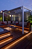 CONTEMPORARY FORMAL ROOF TERRACE/ GARDEN DESIGNED BY DATA NATURE ASSOCIATES: DECK AREA WITH PERGOLA  TABLE  SEATING AND CUSHIONS. JACUZZI AND BAMBOOS. NIGHT. LIGHTING